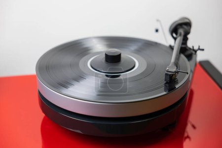 Photo for Close-up view of hi-fi audio record player with black vinyl disk elegantly positioned on red high-quality hi-fi stand, playing captivating tune. - Royalty Free Image