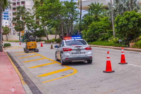 Téléchargez les photos : Vue de la voiture de police avec ses lumières sur le toit debout sur l'une des rues de Miami Beach, qui est limitée à la circulation en raison des travaux routiers. États-Unis. Miami Beach. - en image libre de droit