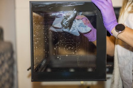 Foto de Vista de cerca de las manos femeninas limpiando el vidrio de la chimenea de hollín en el apartamento. Países Bajos. - Imagen libre de derechos