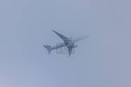Photo for Close-up view of a flying airplane entering into the clouds. USA. - Royalty Free Image