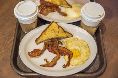 Foto de Vista de cerca de la bandeja con desayuno en el aeropuerto de Miami con tocino al horno, huevos y café en taza desechable. - Imagen libre de derechos