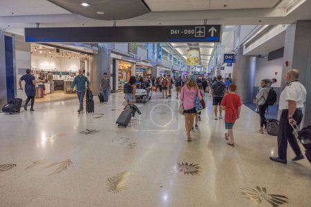 Photo for Interior view of Miami International Airport capturing the dynamic flow of passengers navigating with their luggage through the bustling terminal. Miami. USA. - Royalty Free Image