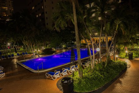 Photo for A beautiful night view at the Radisson hotel, where palm trees and an illuminated open pool contribute to a charmingly lit and inviting ambiance. Miami Beach. USA - Royalty Free Image