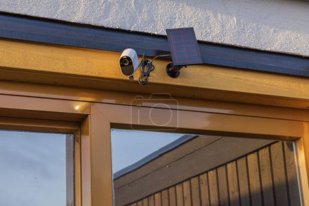 Close-up view of outdoor camera surveillance with solar panel on facade of villa. Sweden.