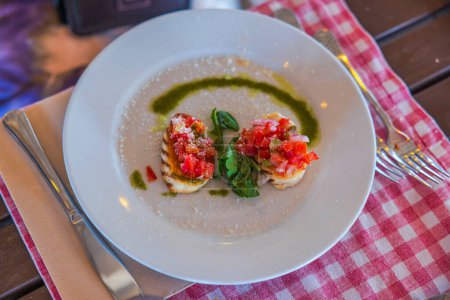 Nahaufnahme eines Tellers mit zwei Sandwiches, garniert mit fein geschnittenen Tomaten, Spinatblättern und geriebenem Parmesan. Curaçao.