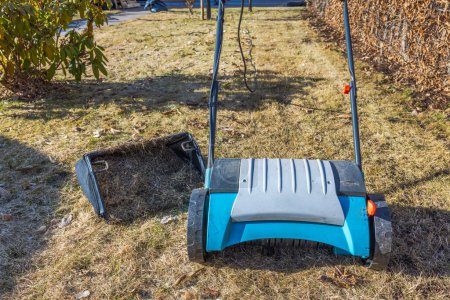 Close-up of an electric lawn aerator and a removed basket of collected dry yellow grass. Sweden.
