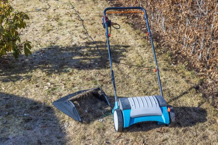 Vue rapprochée d'un aérateur de pelouse électrique et d'un panier rempli de tontes d'herbe sèche fraîchement cueillies. Suède.