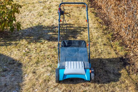 Gros plan d'un aérateur de pelouse électrique sur l'herbe sèche d'hiver dans le jardin un jour de printemps. Suède.
