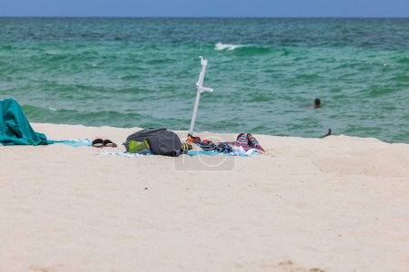 Persönliche Gegenstände, die achtlos auf einem Sandstrand verstreut wurden. Miami Beach. USA.