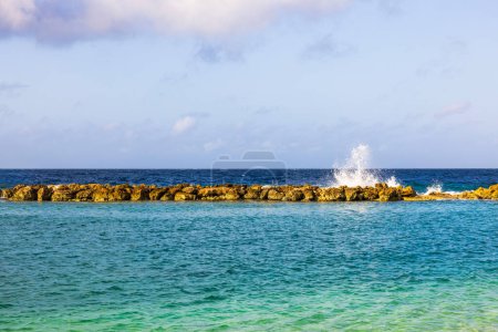 Schöne Aussicht auf das karibische Meer mit einem künstlichen Wellenbrecher, wo die Wellen auf die Felsen krachen. Curaçao.