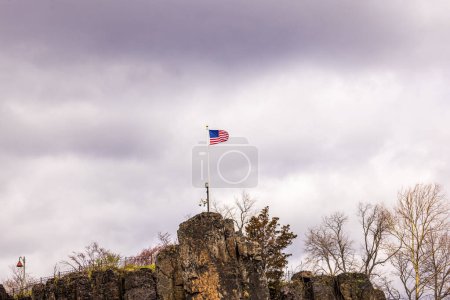 Beautiful view of the American flag flying high on a mountain near Peterson Falls in New Jersey. USA.