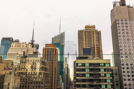 Panoramic view of a dense urban skyline in New York City, showcasing a mix of modern glass skyscrapers and traditional architecture under an overcast sky. New York. 
