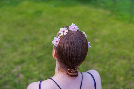 Nahaufnahme eines jungen Mädchens, das ein Haar-Accessoire trägt und auf den lebhaften grünen Rasen blickt. Schweden.