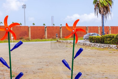 Beautiful view of colorful windmill decorations with blue bottles and orange blades in an outdoor setting against a clear sky. Curacao.