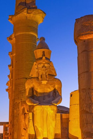 Photo de nuit de la statue assise de Ramsès II. par l'entrée du temple de Louxor. Louxor, Égypte