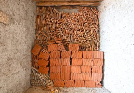 Photo for Stack of terracotta roof tiles in an old garage, France - Royalty Free Image