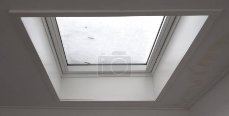 Téléchargez les photos : Vue à travers la fenêtre du toit couverte de neige fondue de l'intérieur du bâtiment, mise au point sélective - en image libre de droit