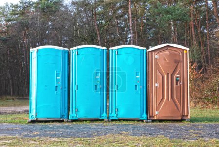 Téléchargez les photos : Quatre toilettes mobiles sur une rangée dans la forêt néerlandaise - en image libre de droit