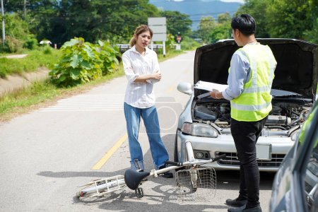 Foto de An insurance agent is asking a female driver about a bicycle crash on road. - Imagen libre de derechos
