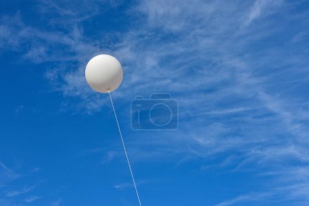 Téléchargez les photos : Ballon blanc. Un ballon publicitaire blanc gonflable géant flotte dans le ciel bleu ensoleillé. - en image libre de droit