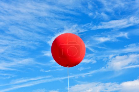 Téléchargez les photos : Ballon rouge. Un ballon publicitaire rouge gonflable géant flotte dans le ciel bleu ensoleillé. - en image libre de droit