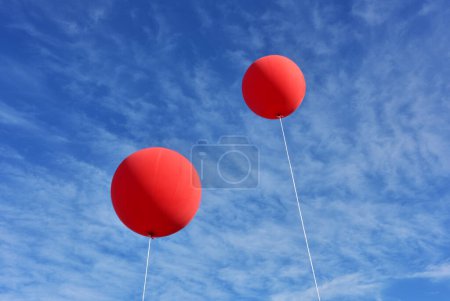 Foto de Globos rojos. Un globo inflable gigante de la publicidad roja flota en el cielo azul soleado - Imagen libre de derechos