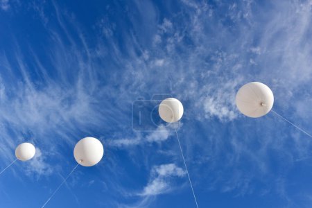 Téléchargez les photos : Des ballons blancs. Un ballon publicitaire blanc gonflable géant flotte dans le ciel bleu ensoleillé. - en image libre de droit