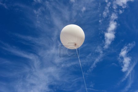 Téléchargez les photos : Ballon blanc. Un ballon publicitaire blanc gonflable géant flotte dans le ciel bleu ensoleillé. - en image libre de droit