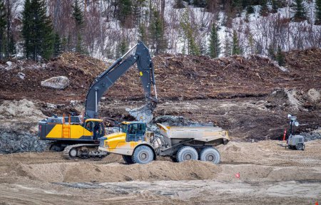 Photo for Excavator and a dumper working on a construction site, in winter - Royalty Free Image