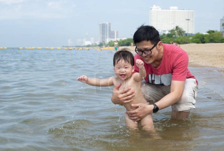 Foto de Asiático padre y bebé niño jugar en la playa juntos en vacaciones. - Imagen libre de derechos
