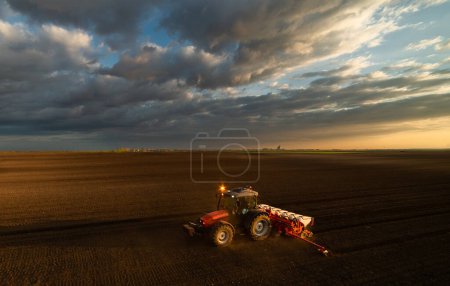 Foto de Agricultor con siembra de tractores - siembra de cultivos en campos agrícolas al atardecer - Imagen libre de derechos