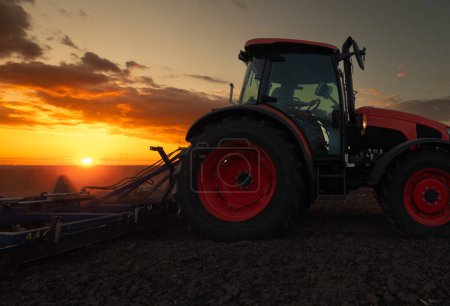 Tractor arando granja preparando el suelo para la nueva plantación de cultivos durante la noche.