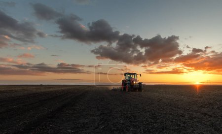 Exploitation de labour de tracteurs préparant le sol pour la plantation de nouvelles cultures pendant la soirée.