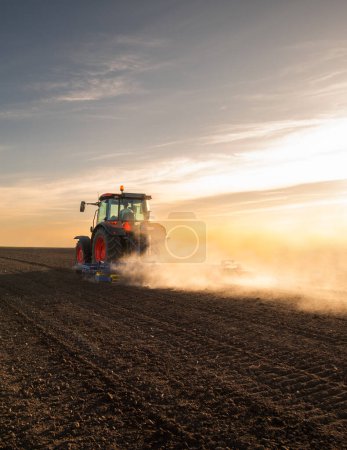 Foto de Tractor arando granja preparando el suelo para la nueva plantación de cultivos durante la noche. - Imagen libre de derechos