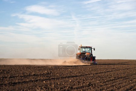 Photo for Tractor plowing farm preparing soil for new crop plantation during the evening. - Royalty Free Image