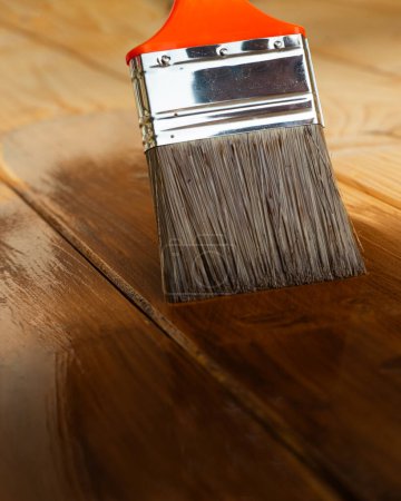 Cepillo que cubre tablones de madera y vigas con barniz para trabajos interiores 