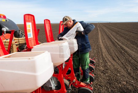 Foto de Granjero cargando semillas a sembradora - Imagen libre de derechos