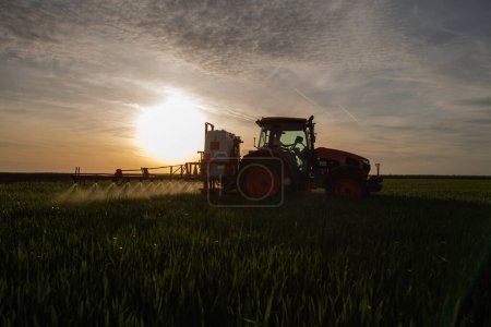 Tractor rociando pesticidas sobre un campo verde
