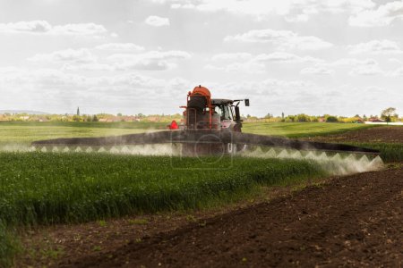 Foto de Tractor rociando pesticidas sobre un campo verde - Imagen libre de derechos