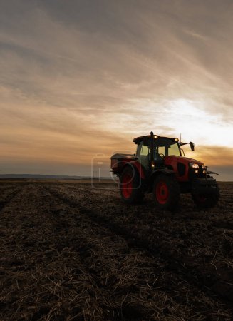 Photo for Farmer fertilizing arable land with nitrogen fertilizer in sunset - Royalty Free Image