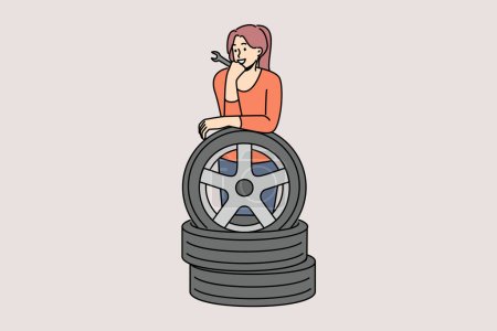 Woman auto mechanic prepares to replace car wheels during vehicle maintenance or repair. Happy girl auto mechanic with wrench in hands leans on tires, rejoicing at possibility replacing them on own