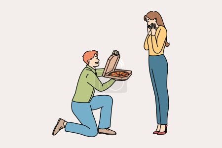 Man gives pizza to beloved, standing on knee and delighting girlfriend with fresh food from italian restaurant. Cheerful boyfriend proposes marriage to girl, with pizza instead of wedding ring