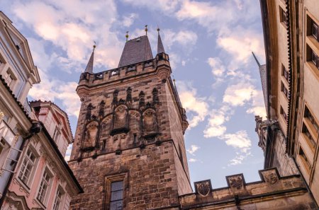 Téléchargez les photos : Vue du matin sur le sommet d'une tour médiévale en pierre avec des statues sur un ancien pont à Prague, en République tchèque. Promenade estivale tardive dans le centre historique médiéval. - en image libre de droit