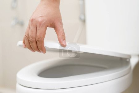 Nahaufnahme einer Frau, die den Deckel eines Toilettensitzes schließt. Hygiene- und Gesundheitskonzept.
