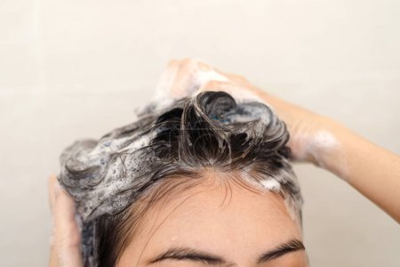 Foto de Mujer tomando ducha y lavando el cabello con champú en el baño en casa - Imagen libre de derechos