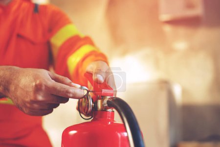 Téléchargez les photos : La main appuie sur l'extincteur de déclenchement disponible dans les situations d'urgence incendie conflagration dommages fond. Sécurité - en image libre de droit