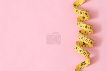 Téléchargez les photos : Ruban à mesurer pour les personnes obèses sur un fond rose soft focus - en image libre de droit