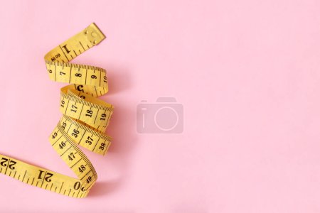 Téléchargez les photos : Ruban à mesurer pour les personnes obèses sur un fond rose soft focus - en image libre de droit