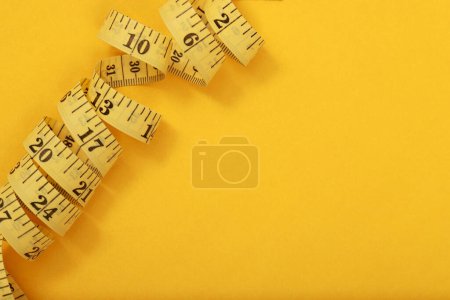 Téléchargez les photos : Ruban à mesurer pour les personnes obèses sur un fond jaune soft focus - en image libre de droit