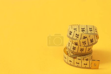 Téléchargez les photos : Ruban à mesurer pour les personnes obèses sur un fond jaune soft focus - en image libre de droit
